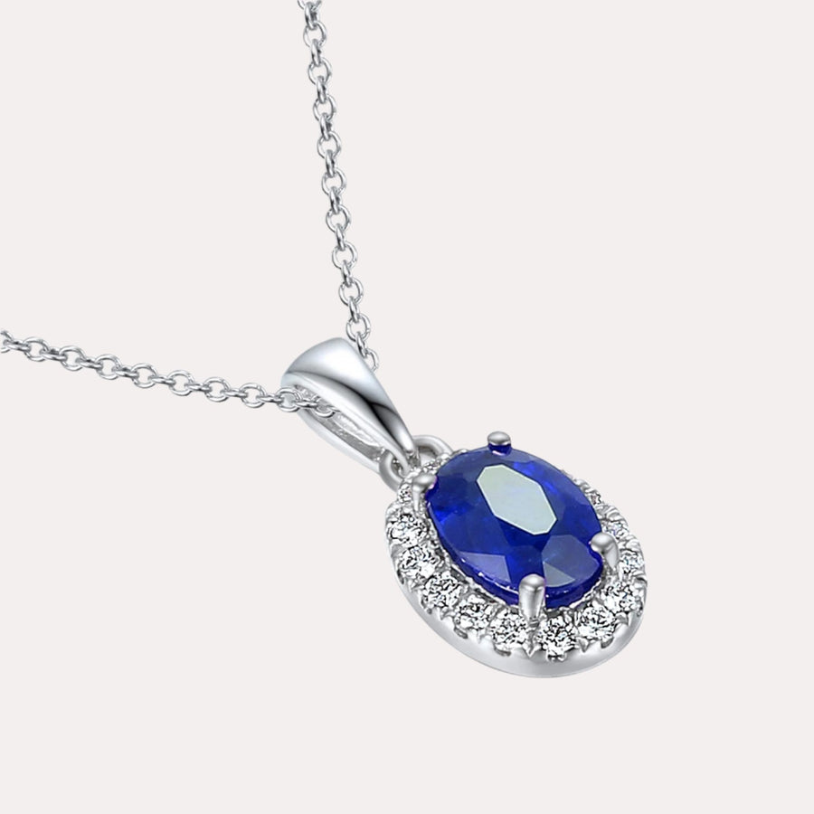 Oval Blue Sapphire With Claw Set Diamond Halo Pendant Necklace In 18K Gold - The Jewelyst. - Oval Blue Sapphire With Claw Set Diamond Halo Pendant Necklace In 18K Gold